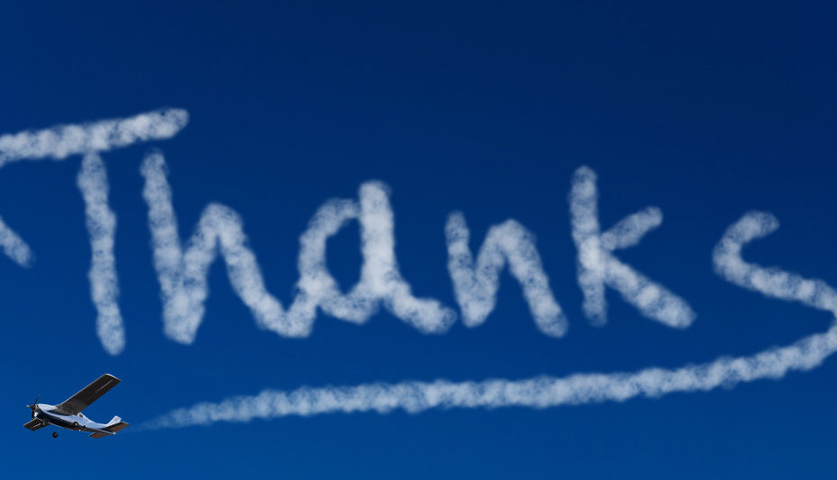 Skywriter writing the word Thanks in the blue sky